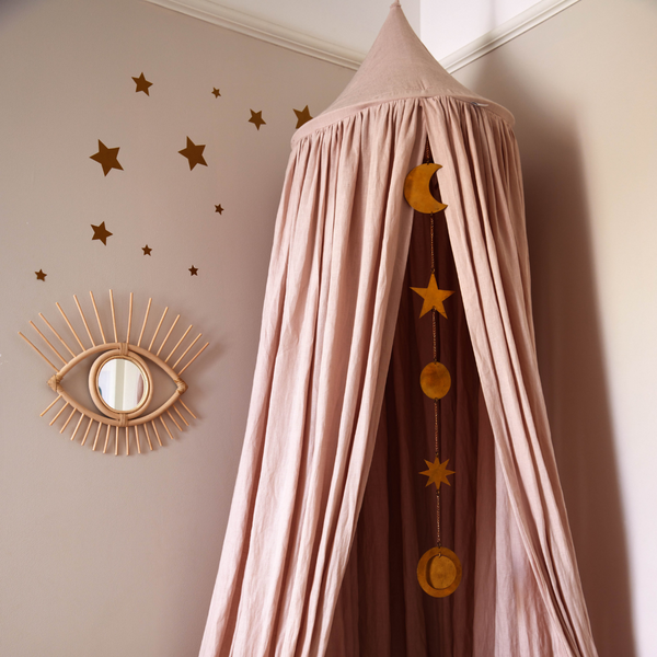 Handmade wooden framed eye mirror on a bedroom wall next to a canopy and brass star Garland 